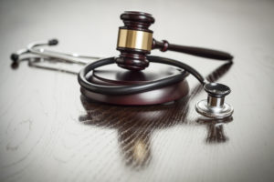 Medical Malpractice Lawyer - Gavel and Stethoscope on Reflective Wooden Table.